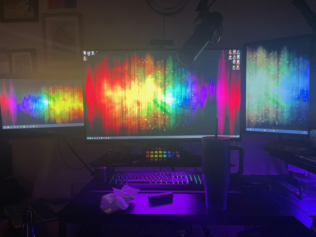 Rainbow patterned desktop background lined up over 3 pc monitors.