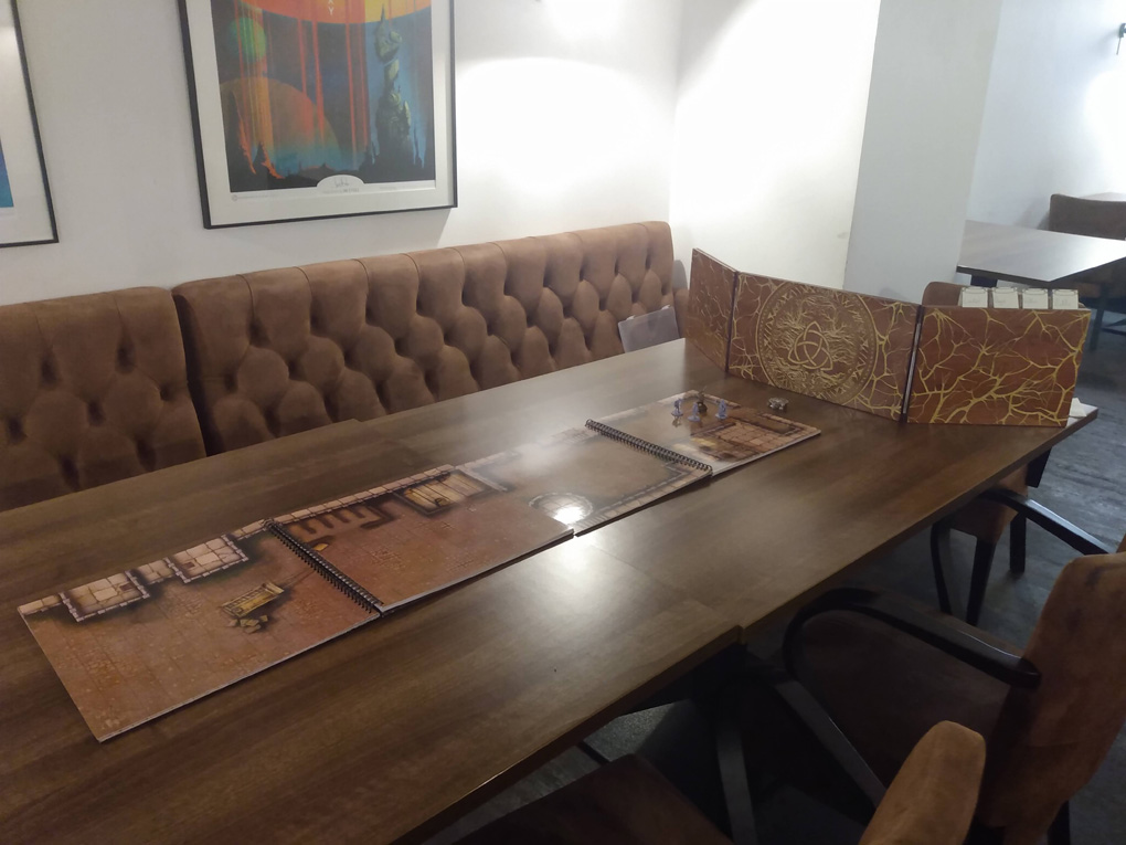 A table with a map, miniatures and dungeon master's screen all set up ahead of play.