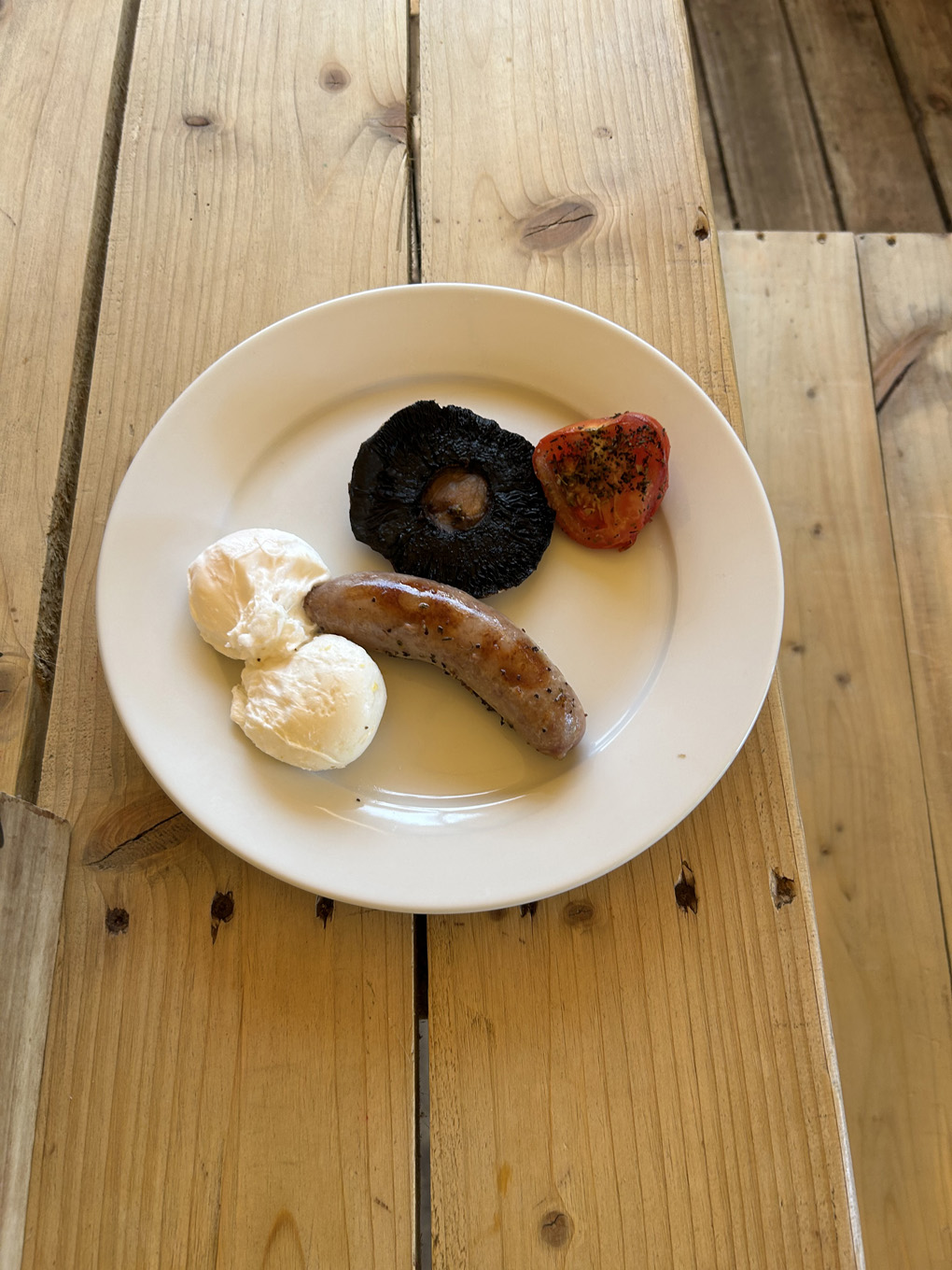 Cooked breakfast on a plate with the two poached eggs and sausage arranged to look like male genitals