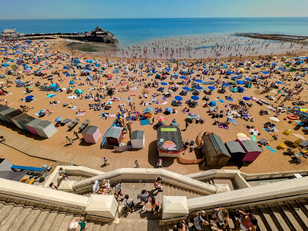 wide-angle hi shot of a beach with lots of people and umbrellas