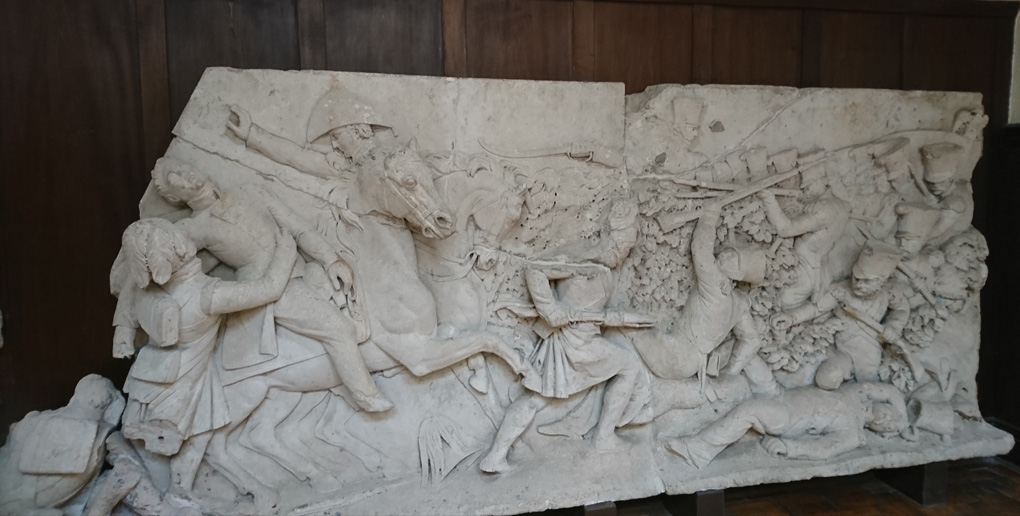 Part of a frieze which was originally on the base of the Picton Monument created in 1827. The frieze looked like it was sculpted out of sandstone with cement and depicts the attack by General Picton on Badajoz and his death falling off his horse into the arms of a soldier of the Highlands Division during the battle of Waterloo in 1815. The Monument was designed by John Nash and made by E.H. Baily in 1827. It stood 23m tall and was replaced by the present obelisk in 1846 as it was then unsafe and unfashionable. It must have been very impressive as the carving was very well done.