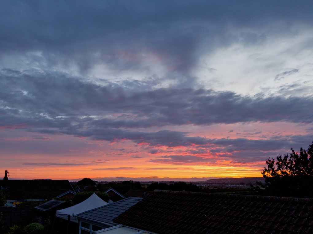A vivid purple and orange sunset, broken up by deep blue clouds.