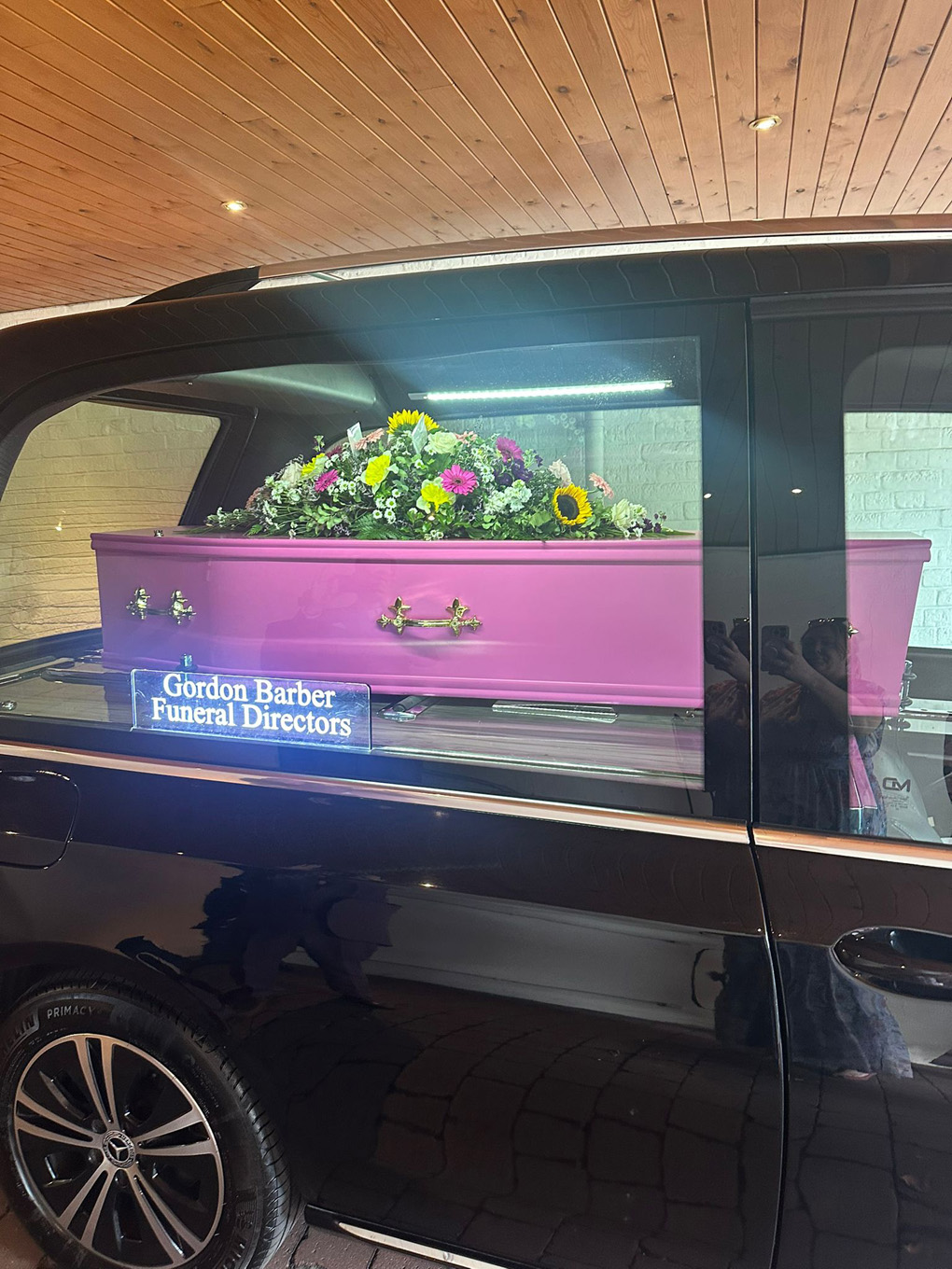 A pink coffin in the back of a hearse