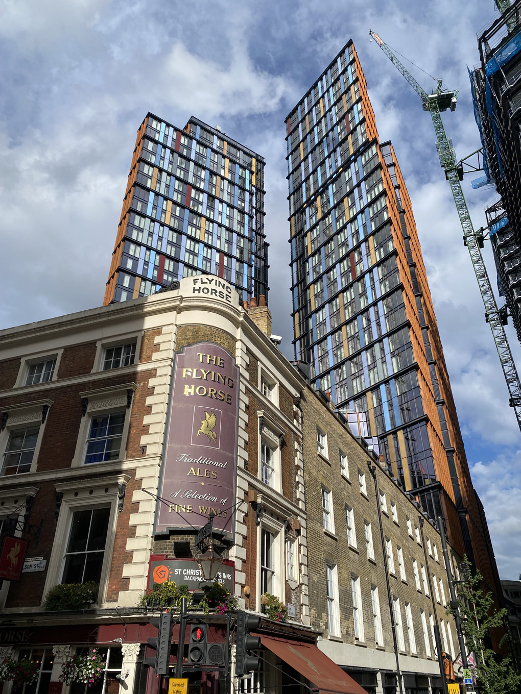 An old London pub in the foreground, juxtaposed with two colourful high-rise blocks in the background.