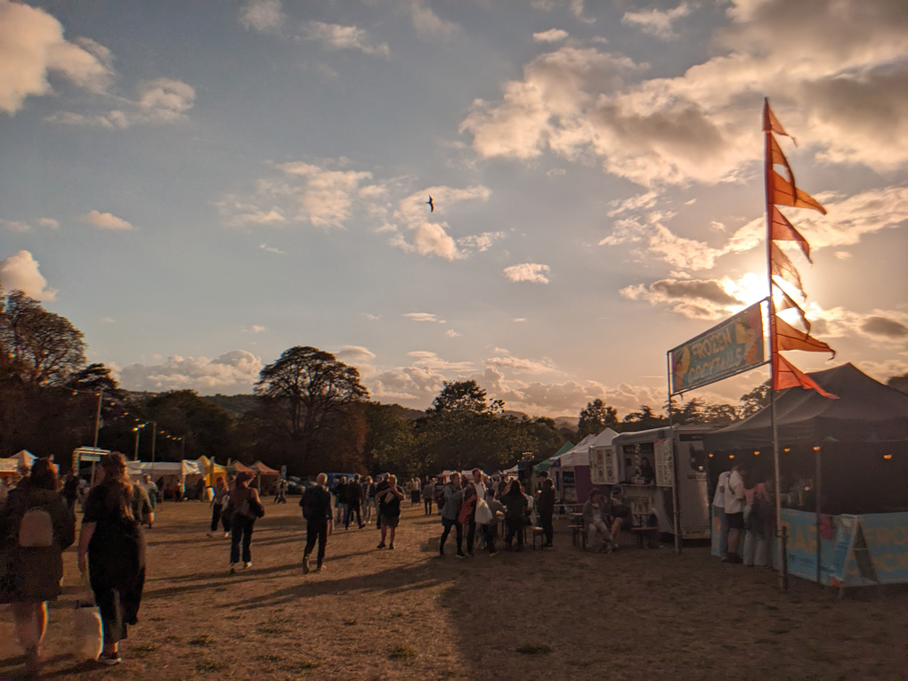 Evening sun, festival tents adorned with flags, view across the hills of Bath