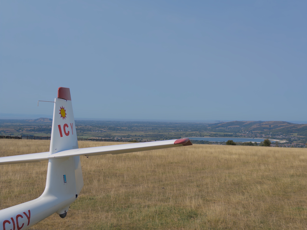 A glider tail in white with red details, displaying a small yellow sun motif above the letters 