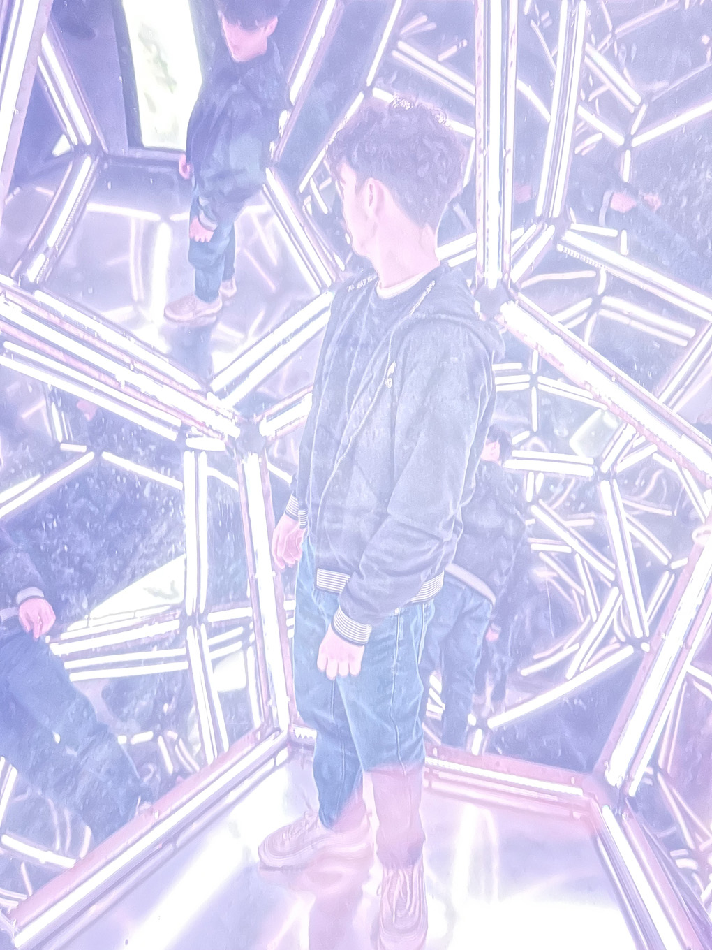Teenage boy in an infinitely reflecting mirror installation