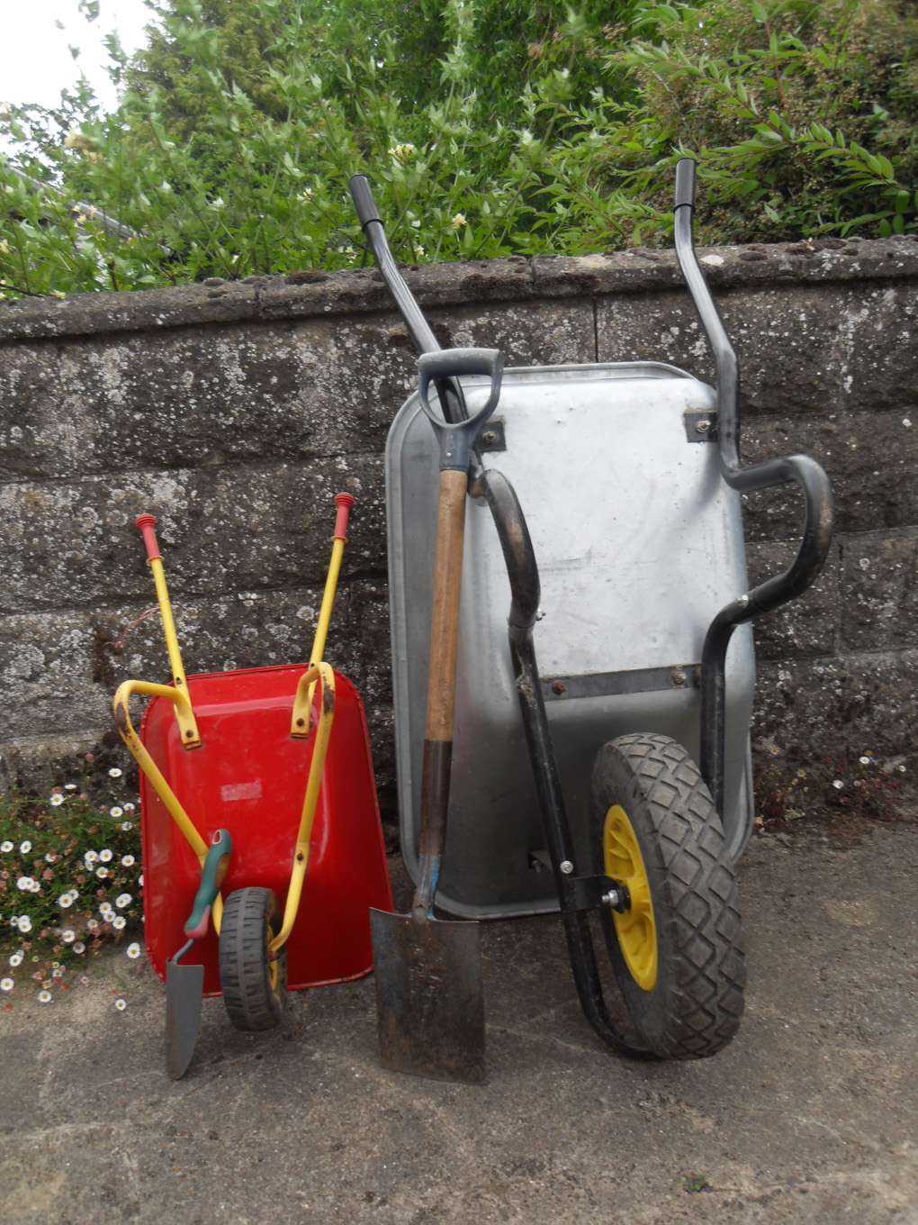 Adult and child wheelbarrows parked against wall