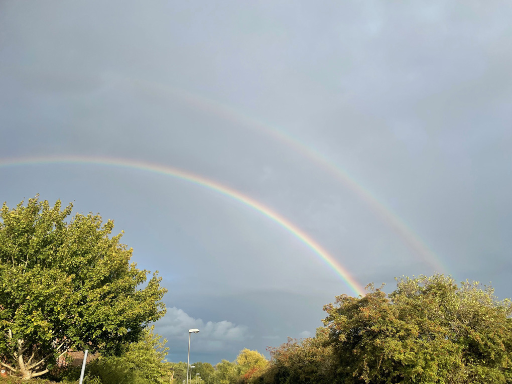 A double rainbow in the midst of dark grey clouds.