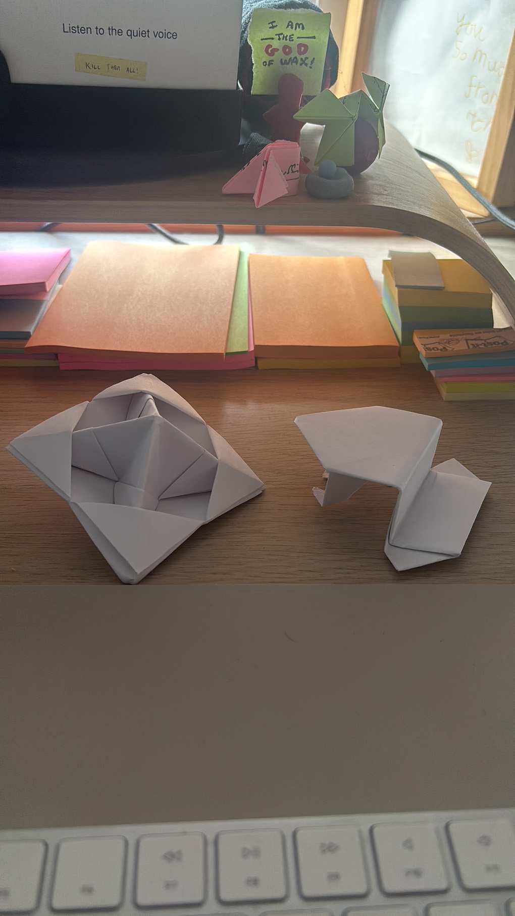 A close up of a folded paper spinning top and hopping frog sat on a wooden table