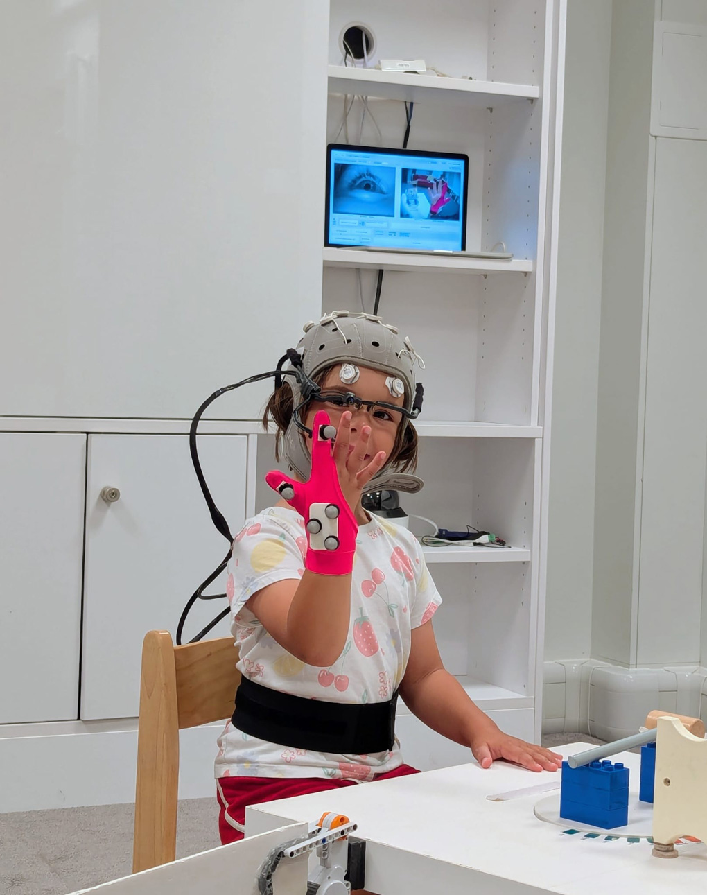 Child wearing electronics in a hat and glove