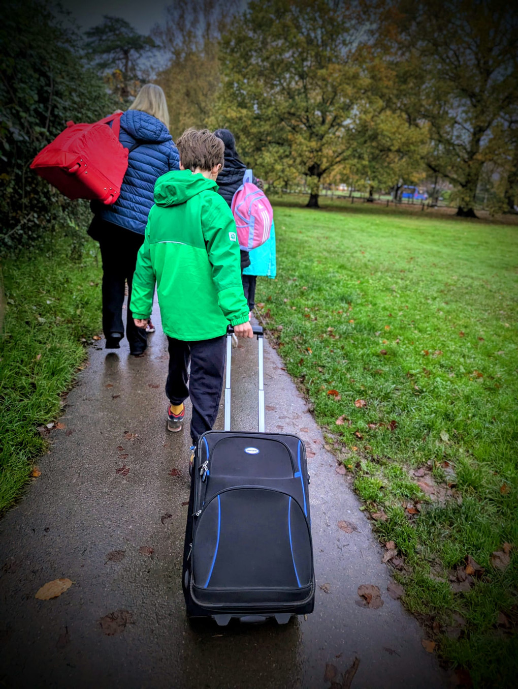 Child pulling suitcase along path