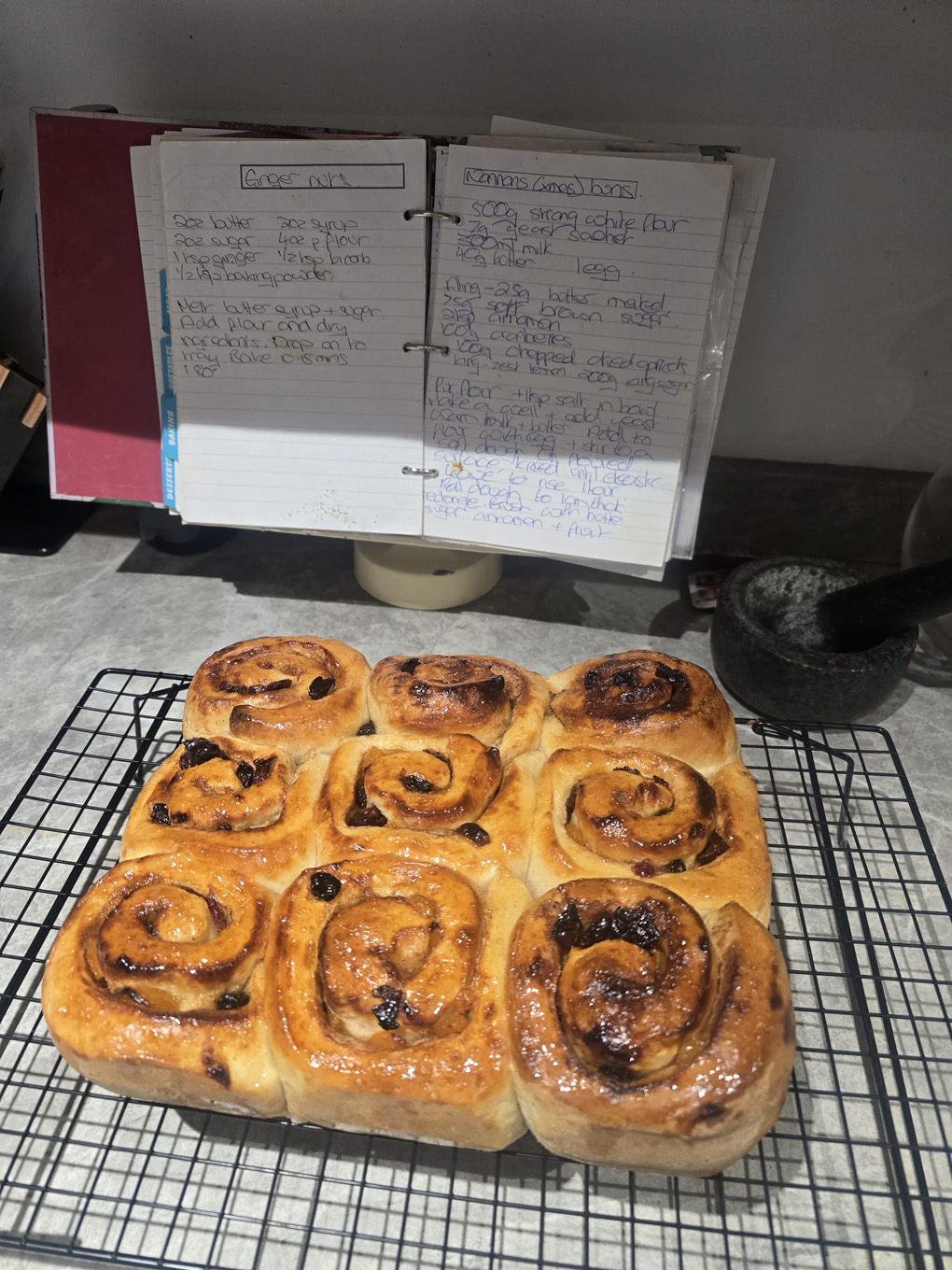 A tray of freshly baked cinnamon buns in front of the recipe