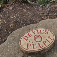 A countryside view from a view point, the name of the view point 'Devil's Pulpit' is on a sign on the ground