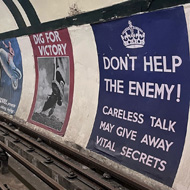 An empty London Underground platform with large mocked up posters from the World War 2 era