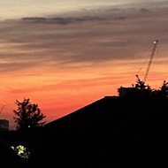 Red/orange sunset over rooftops in distance. Crescent moon and bright Venus in sky.