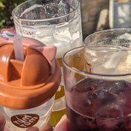 A group of glasses clinked togeter, including a toddler cup with a straw