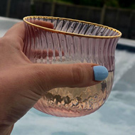 Hand holding a drink in an outdoor bath