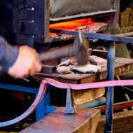 In the foreground the blacksmith is hammering on the curved piece that will hold the lamp in the arch over the new gateway for the church path.