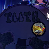 A drum kit on a dark stage crossed with spotlight beams
