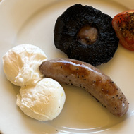 Cooked breakfast on a plate with the two poached eggs and sausage arranged to look like male genitals
