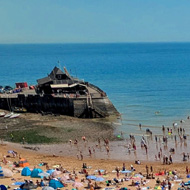 wide-angle hi shot of a beach with lots of people and umbrellas