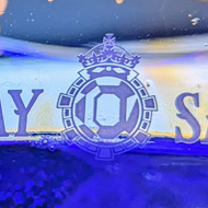 Two glasses of gin and tonic, illuminated in bright blue lights from behind. The etched logo of Bombay Sapphire can be read on the glass