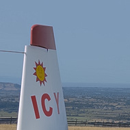 A glider tail in white with red details, displaying a small yellow sun motif above the letters 