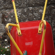 Adult and child wheelbarrows parked against wall