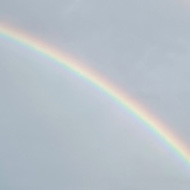 A double rainbow in the midst of dark grey clouds.