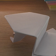 A close up of a folded paper spinning top and hopping frog sat on a wooden table