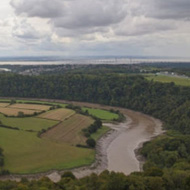 A loop of the muddy River Wye form the centre framed by trees with the Severn Estuary in the background.