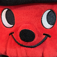 A Henry vacuum cleaner pushie toy with headphones on. On armrest of leather sofa.