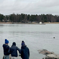 Boys standing by water on the shore.