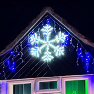 My kids standing in front of a colourful house full of lights pulling a funny face and funny pose.