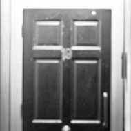 Two women in black and white wait in shadow next to a bright entryway. they are dressed up, probably for a gig at the komedia