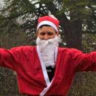 A simple image of a Dad and son dressed as Santas and mum as an elf. They are just finishing the fun run and all hold their arms aloft for the camera.
