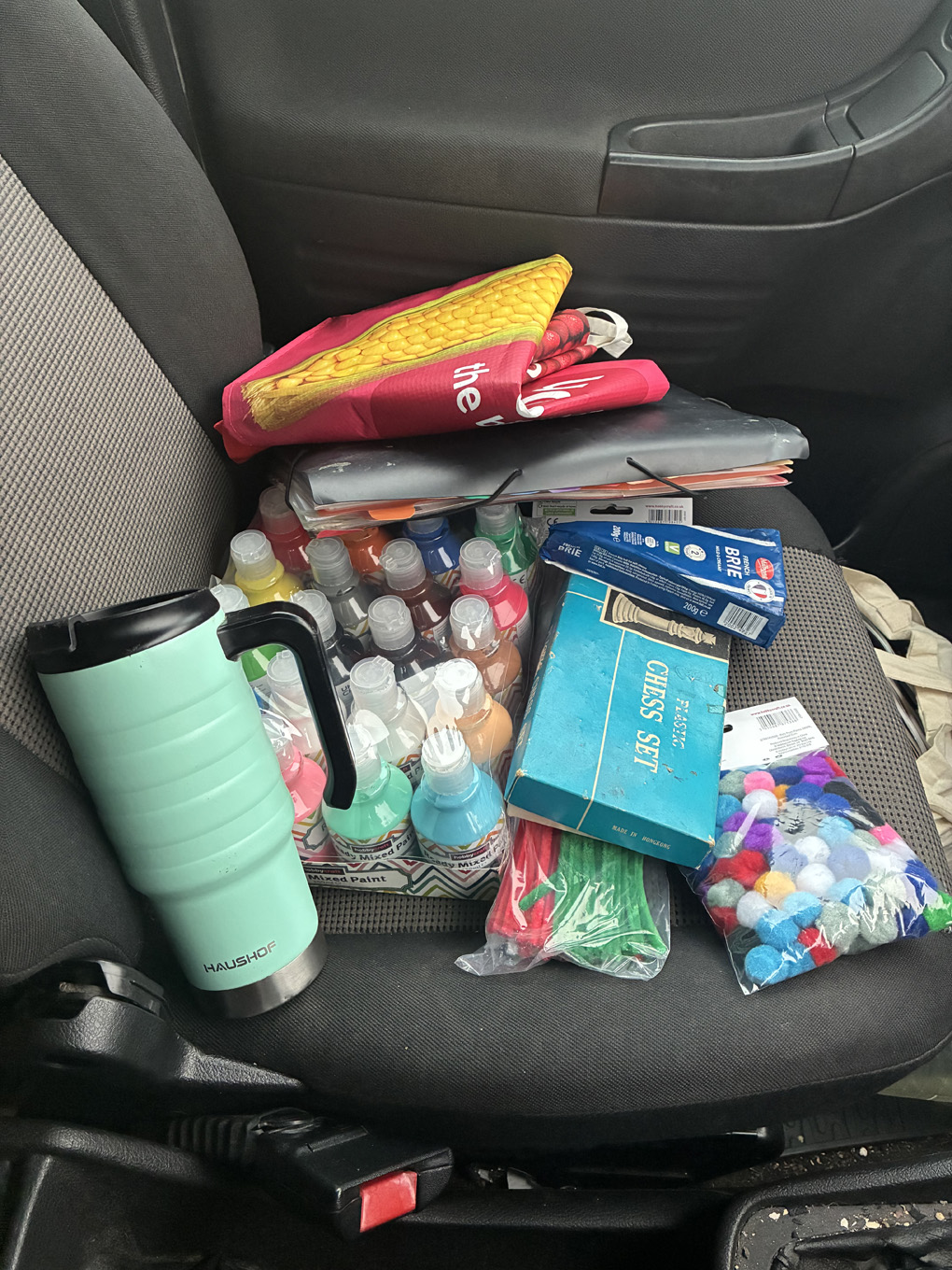 Car front passenger seat, with paint, chess, cheese a folder, a cup, pipe cleaners and Pom poms..