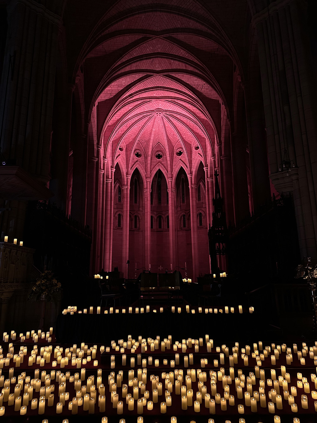 St John's Cathedral lit by candles with small orchestra silhouetted at end.