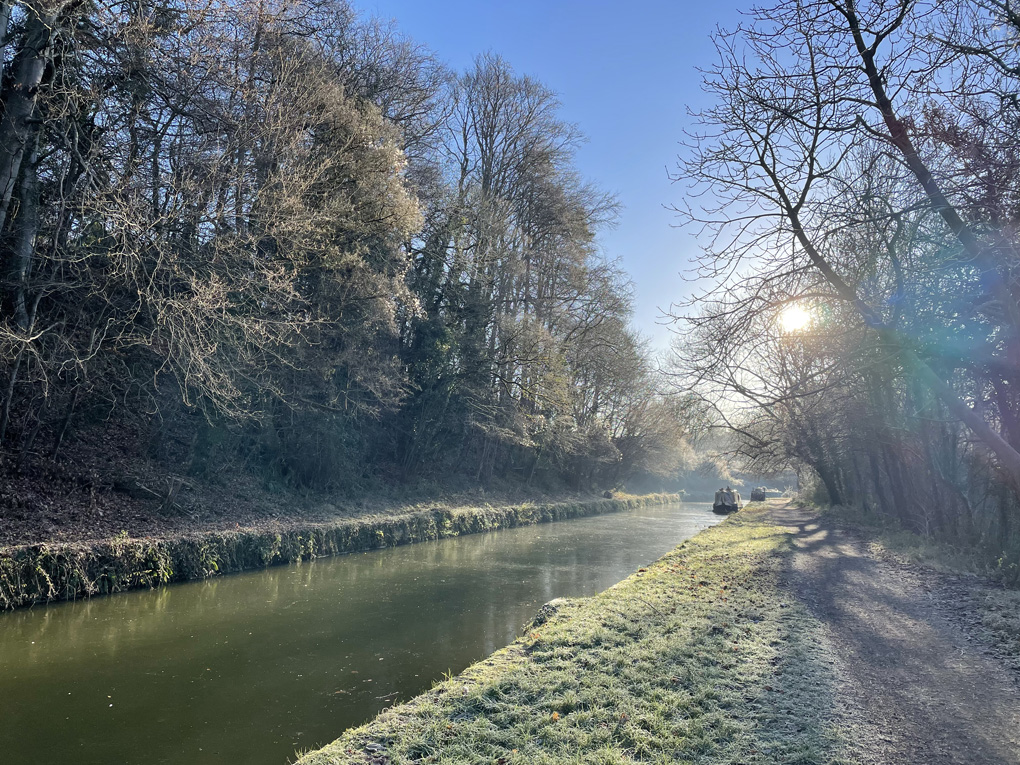 A cold looking canal with trees and a boat in the distance