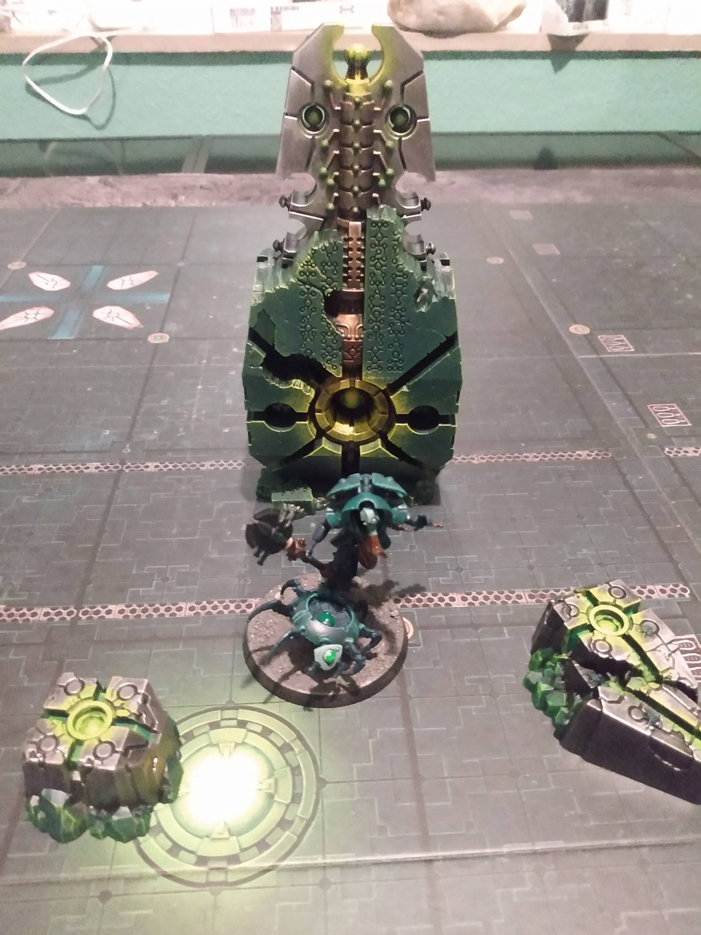 Warhammer models are arranged on a cardboard map, each is silver and glows green
