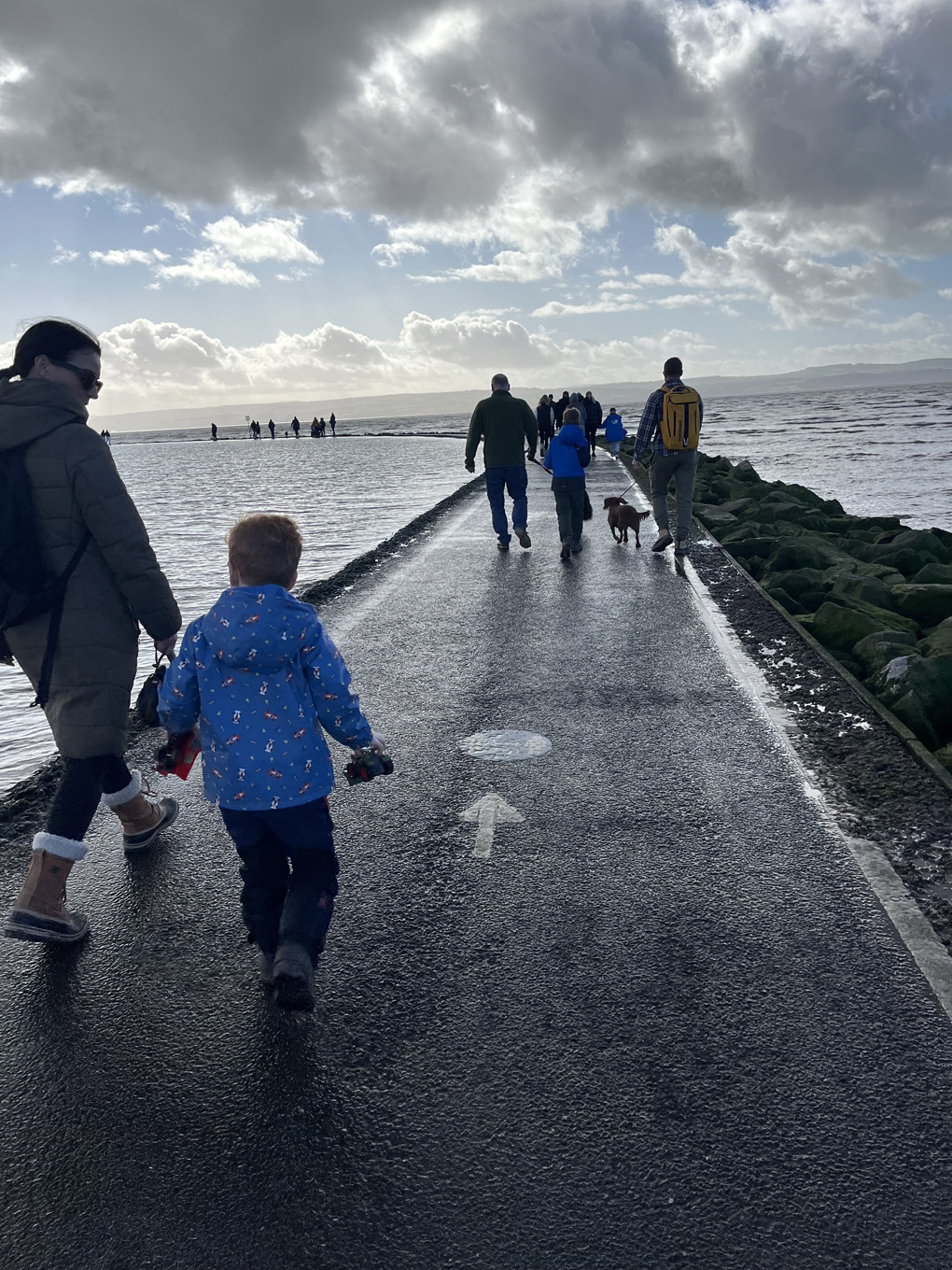 A scene of people walking on a path through the water.
