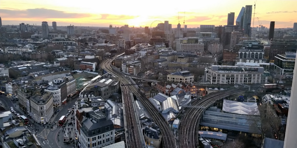 London skyline looking West over Borough Market from an elevated position. The sun sets near the London Eye in the distance.