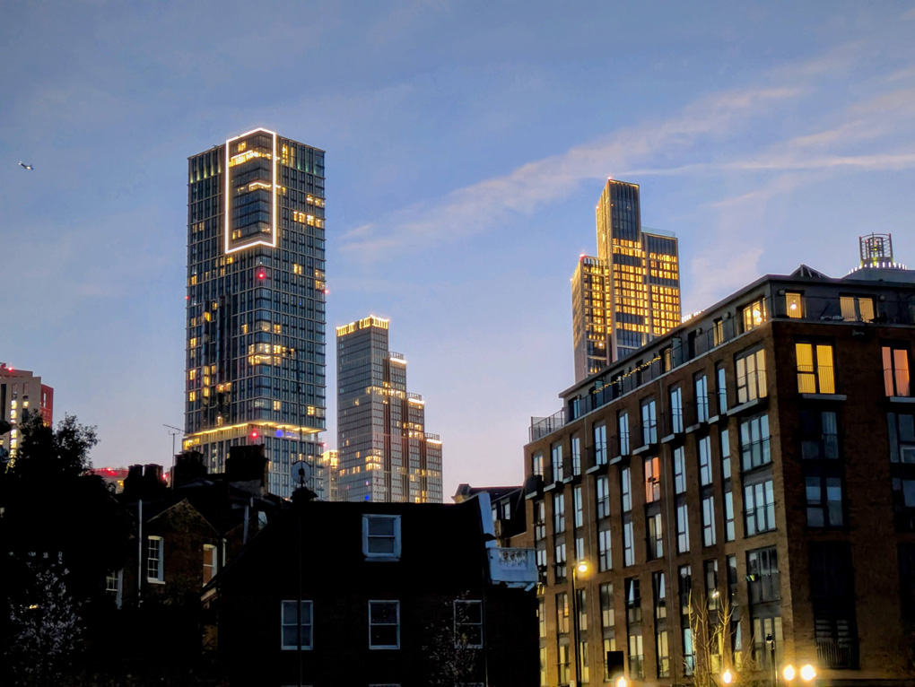 Skyline of tall buildings with lights and the twilight sky.