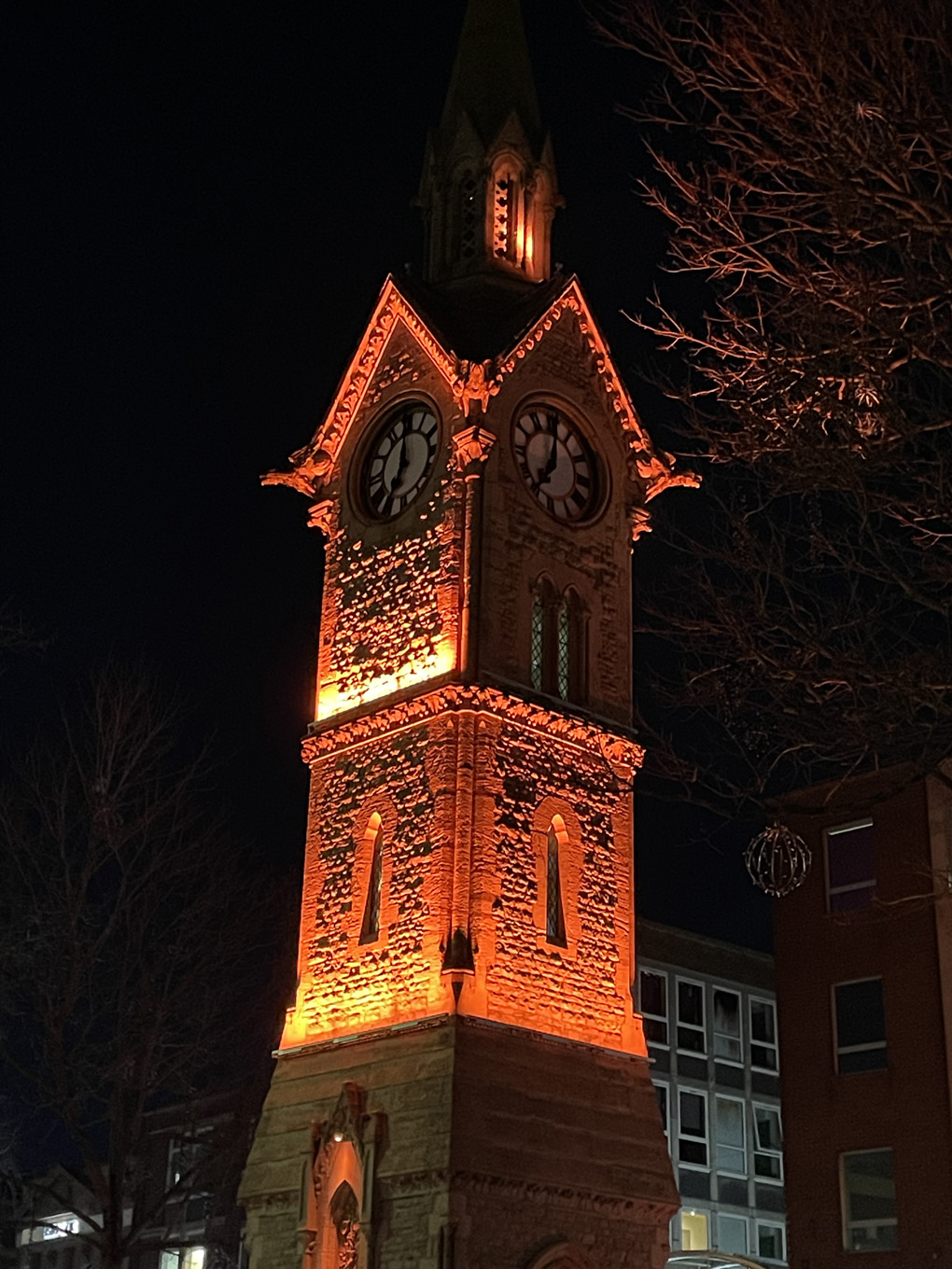 A clock tower, ominously lit in red. stranger things vibes.