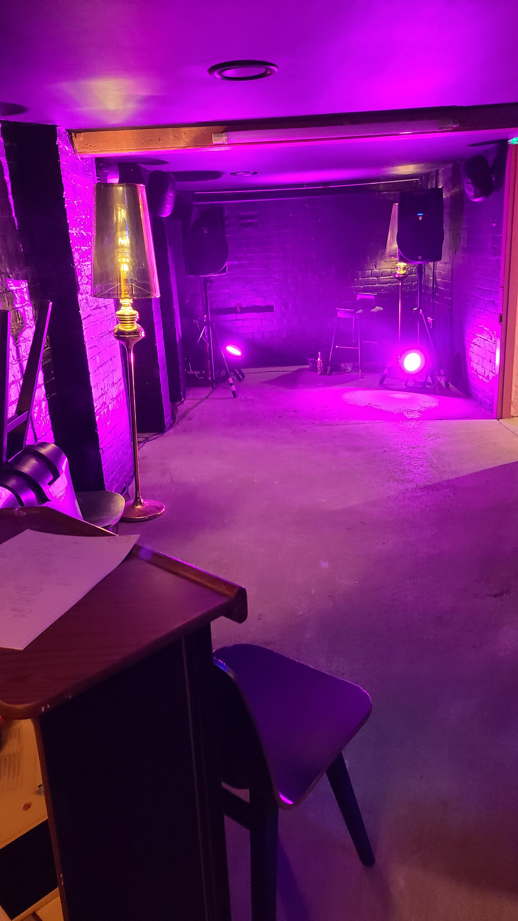 A tiny, garage sized venue with black walls and purple lighting.