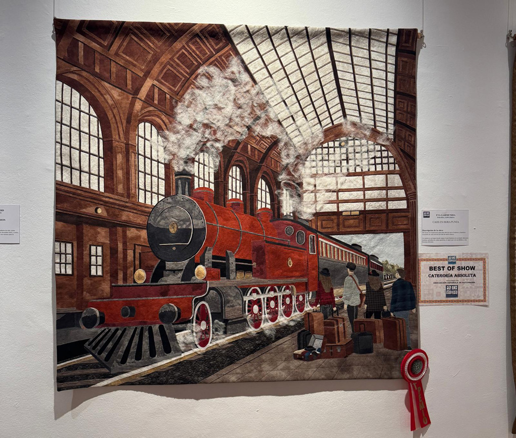An amazing quilted and embroidered panel of a red and black steam train just pulling in to a Victorian looking station with lots of glass windows and glass roof. Passengers with suitcases are waiting on the platform . It’s a fabulous piece created by Eva Garmendia, at a Textile Exhibition in Sitges, Spain. She won ‘Best in Show’ which was well deserved.