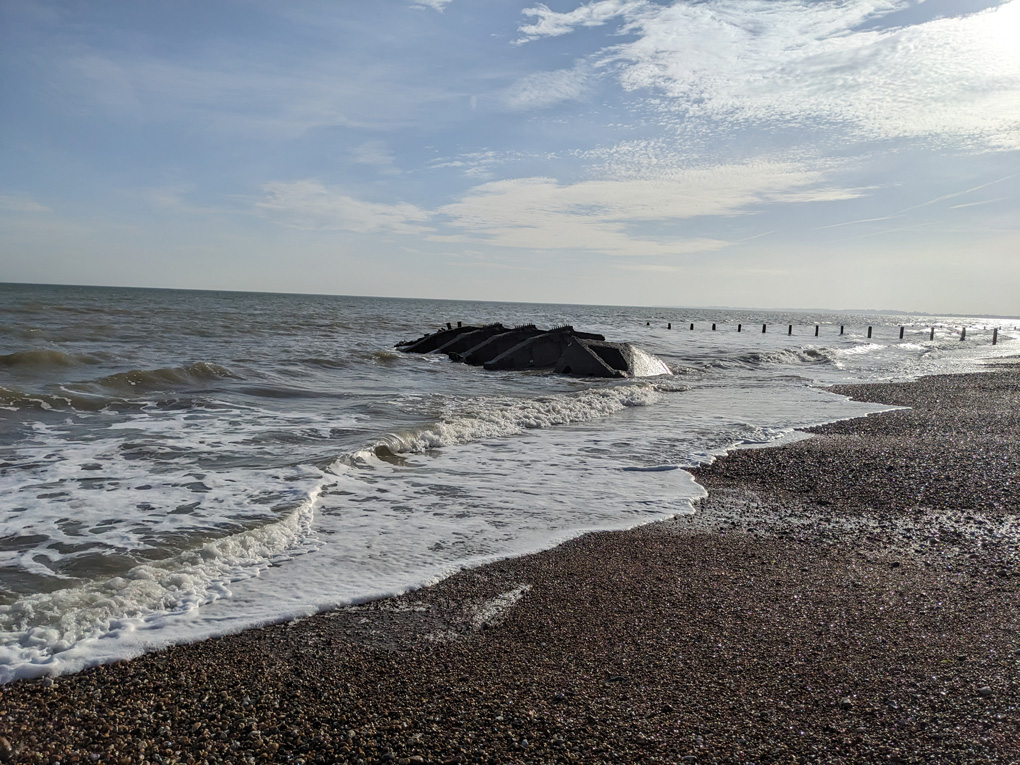 A wreck half exposed by the tide on the beach shore