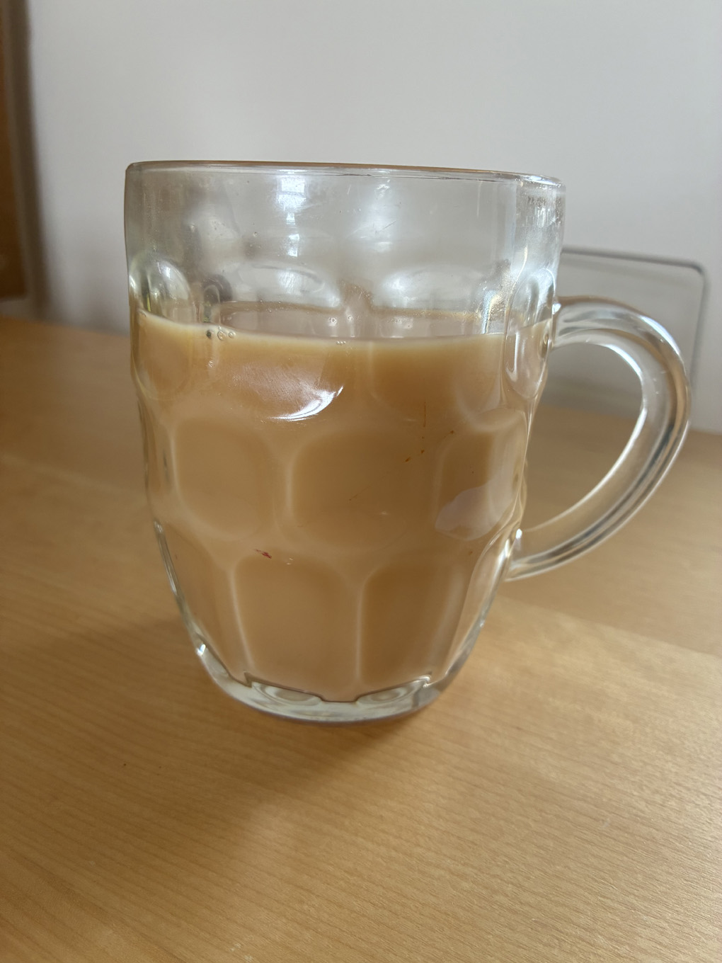 Tea inside a traditional one pint bear glass.sat on a wooden surface.