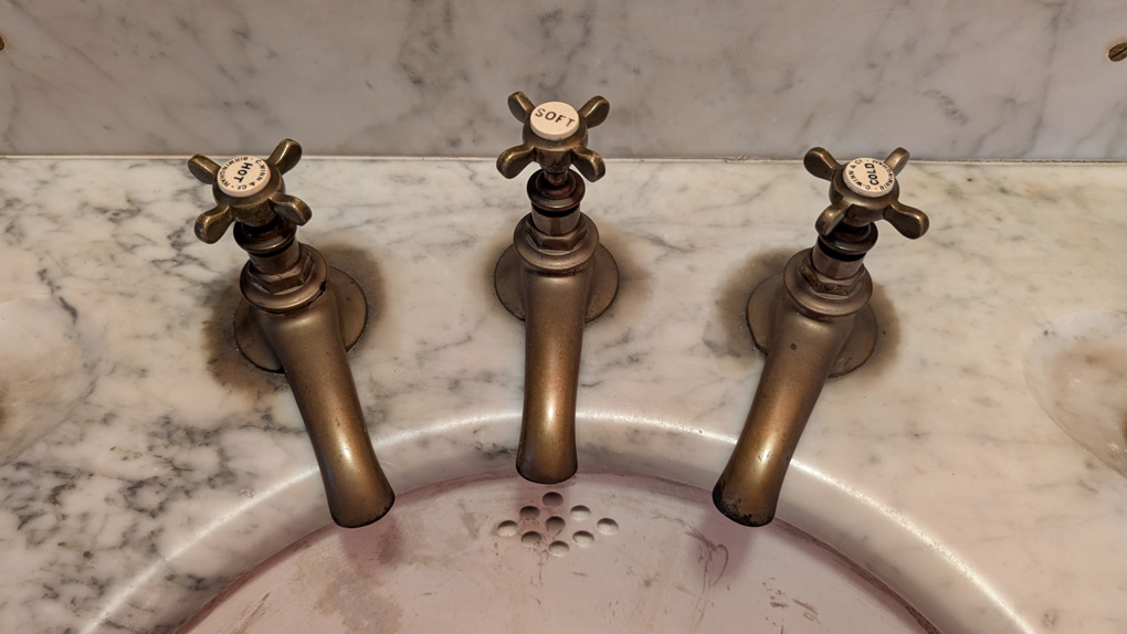 A marble sink with three taps. They are, left to right, Hot, Soft and Cold.